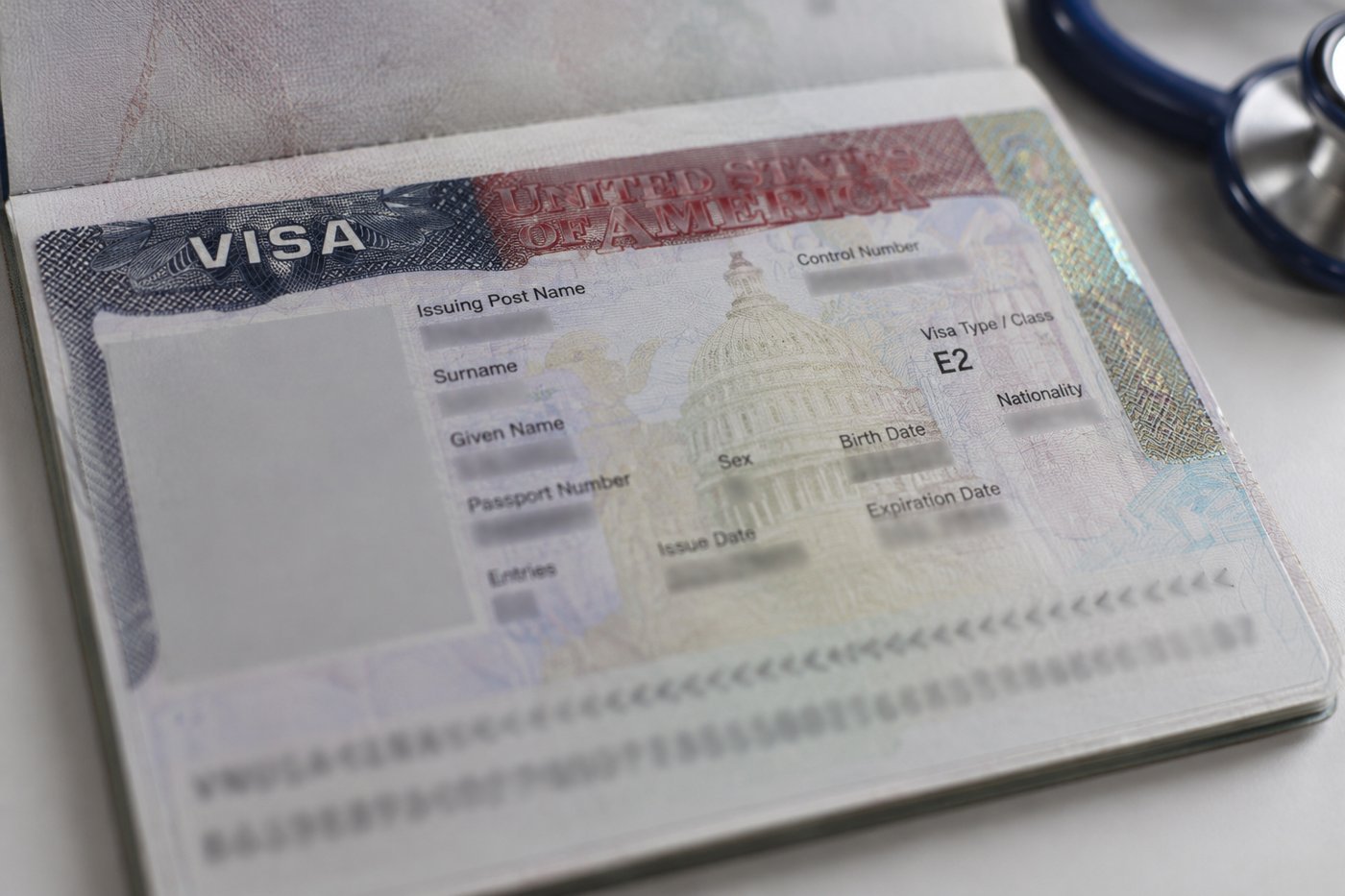 Visa américain E-2 dans un passeport ouvert, à côté d'un stéthoscope